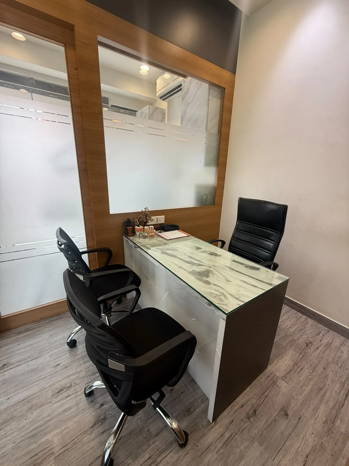 A consultation desk with a marble top, chairs and glass partitions