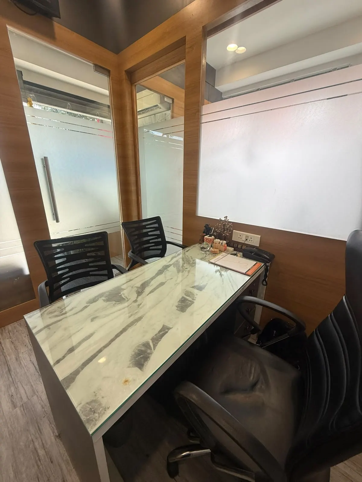 The consultation room seen from the doctor's chair, with wood panelling and a glass door