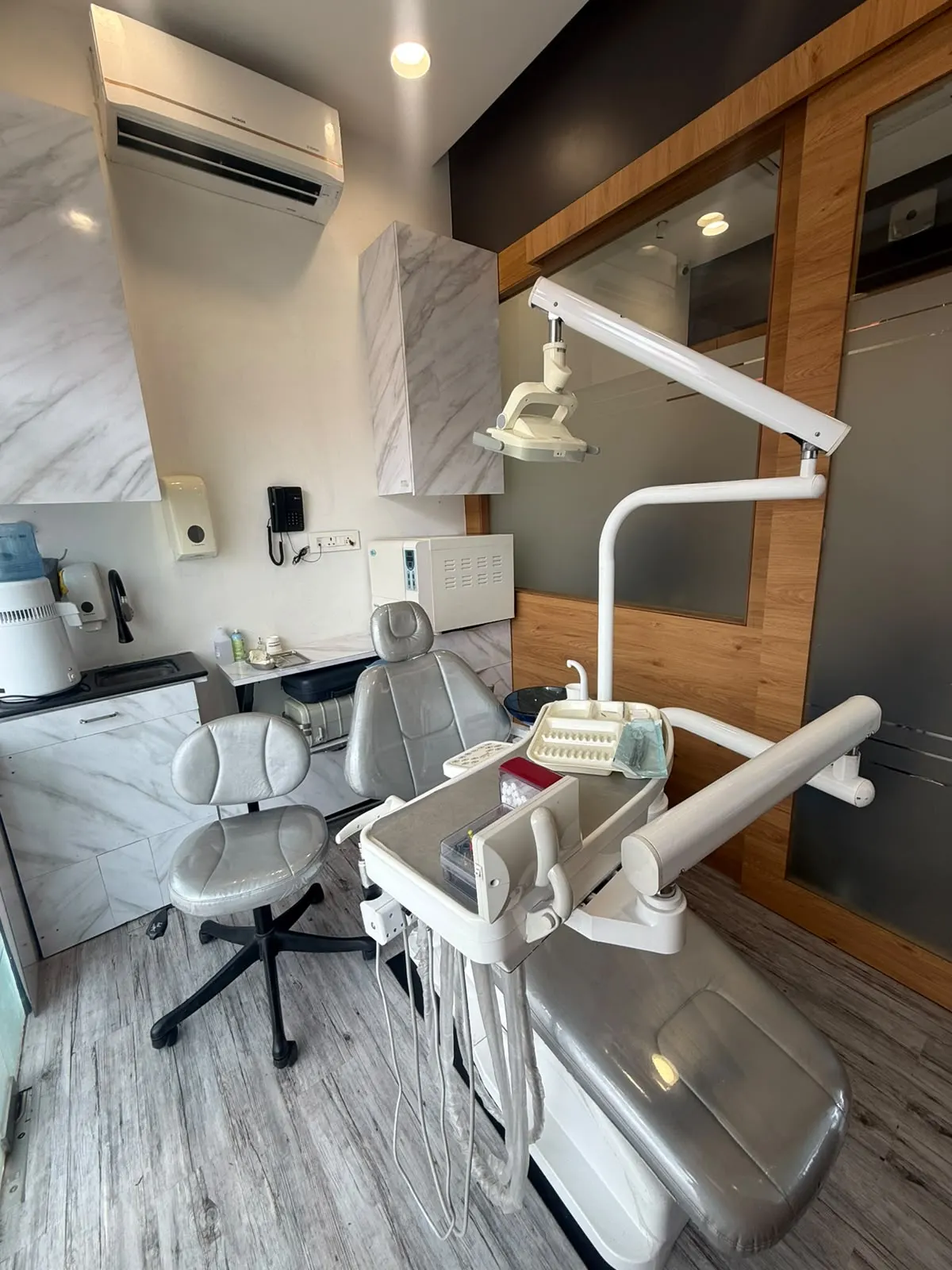 A treatment room with marble-finish cabinets, a dental chair and an autoclave