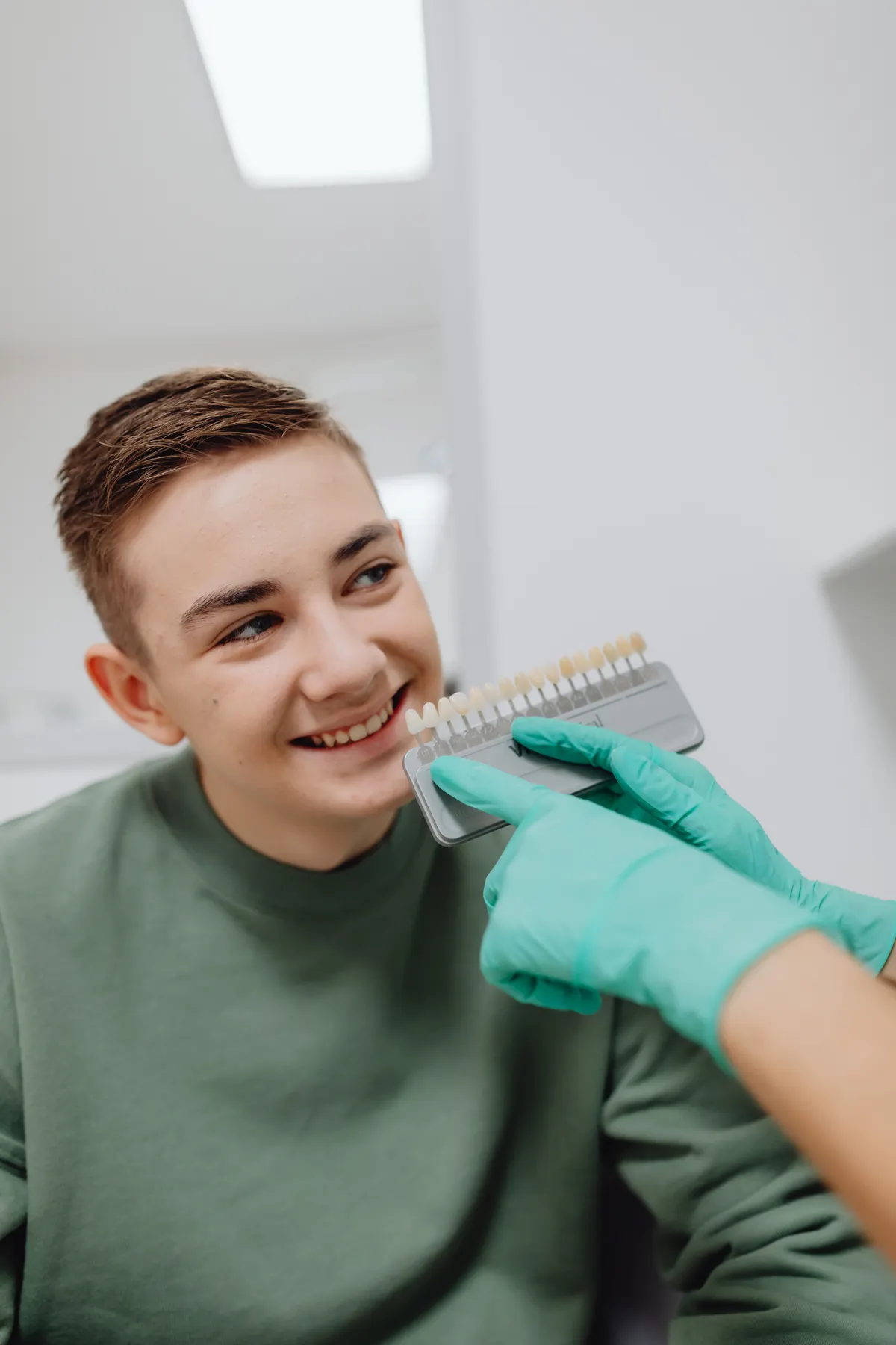 A dentist matching a shade guide to a smiling patient's teeth